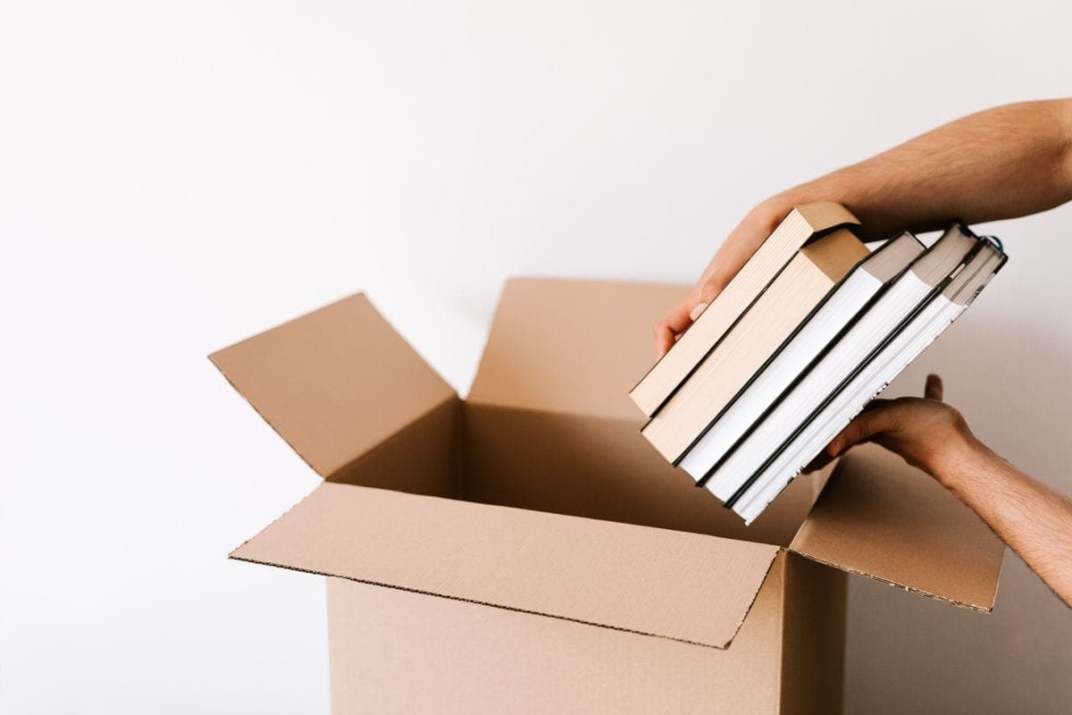 Books being packed into a cardboard moving box