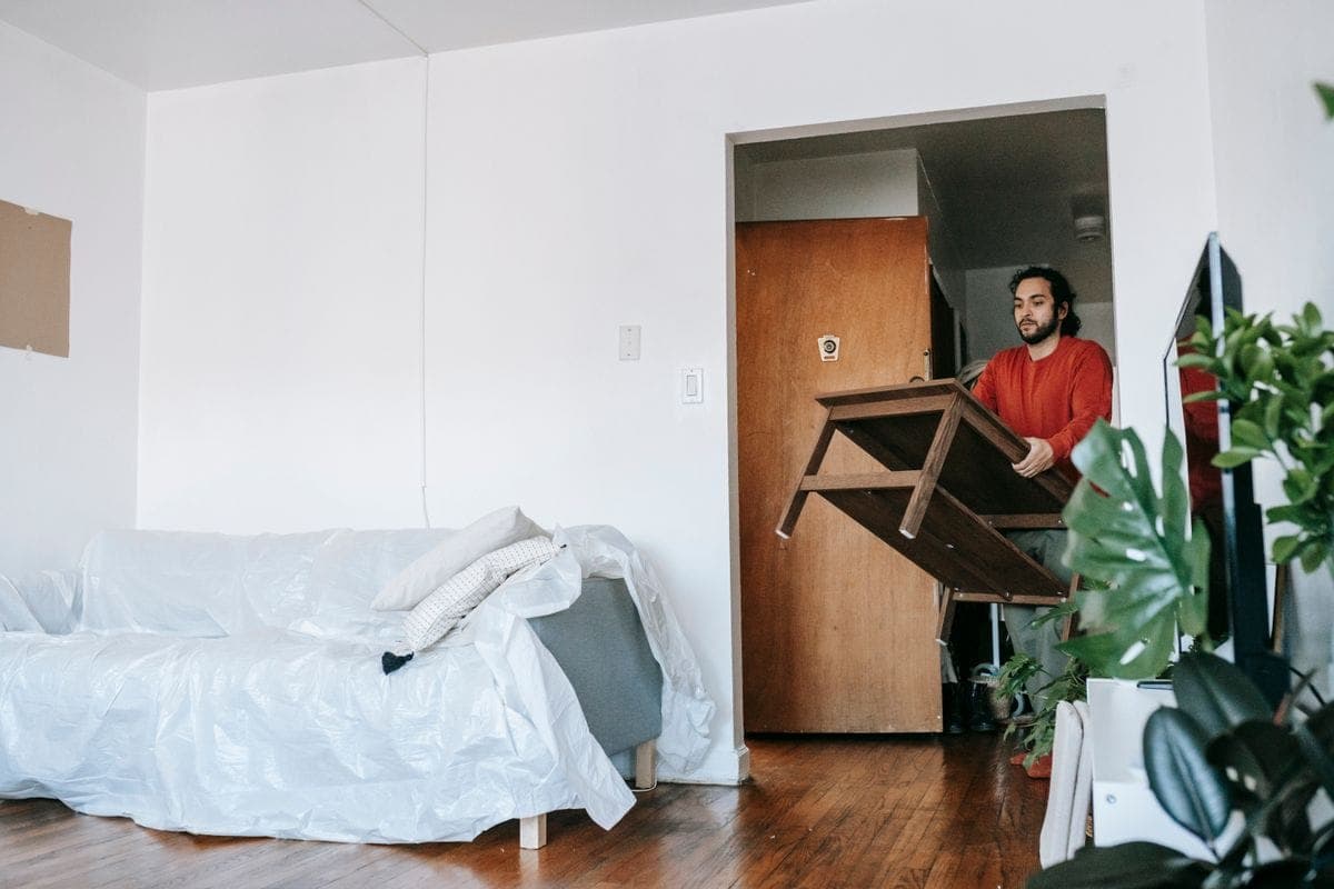 Mover carrying a wooden table out of a flat